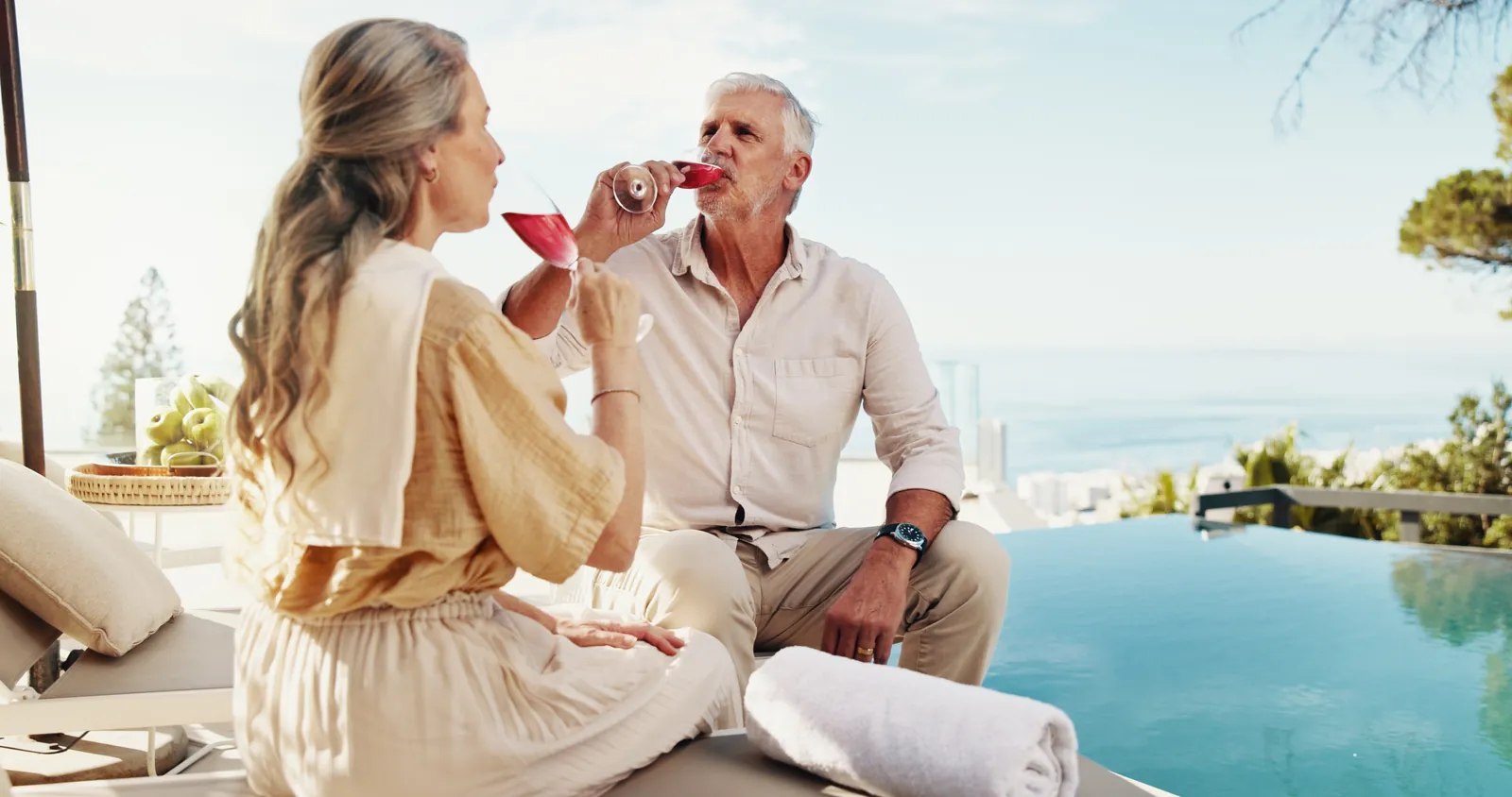 A couple sharing a glass of wine beside an infinity pool