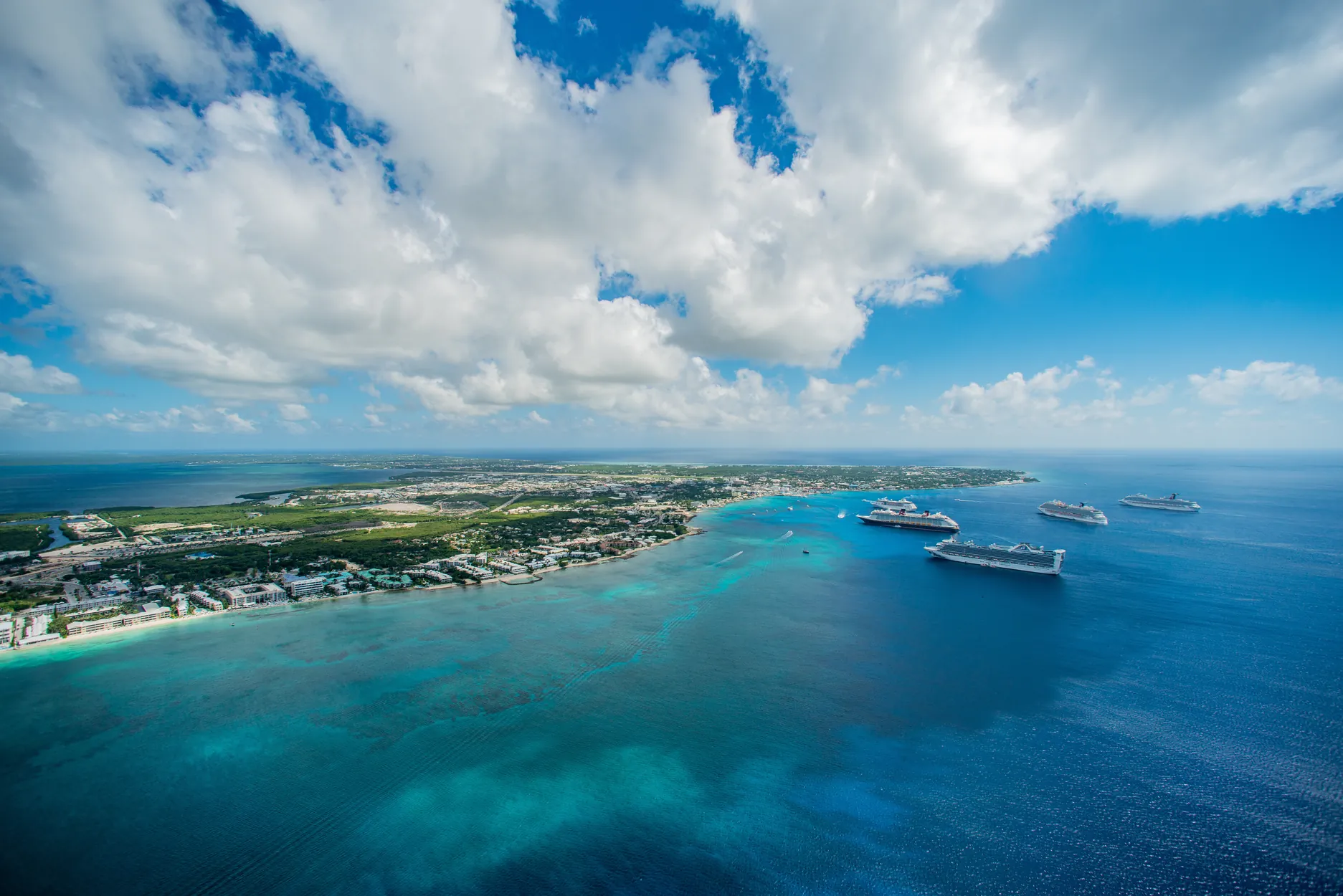 Aerial view of a tropical island with cruise ships offshore